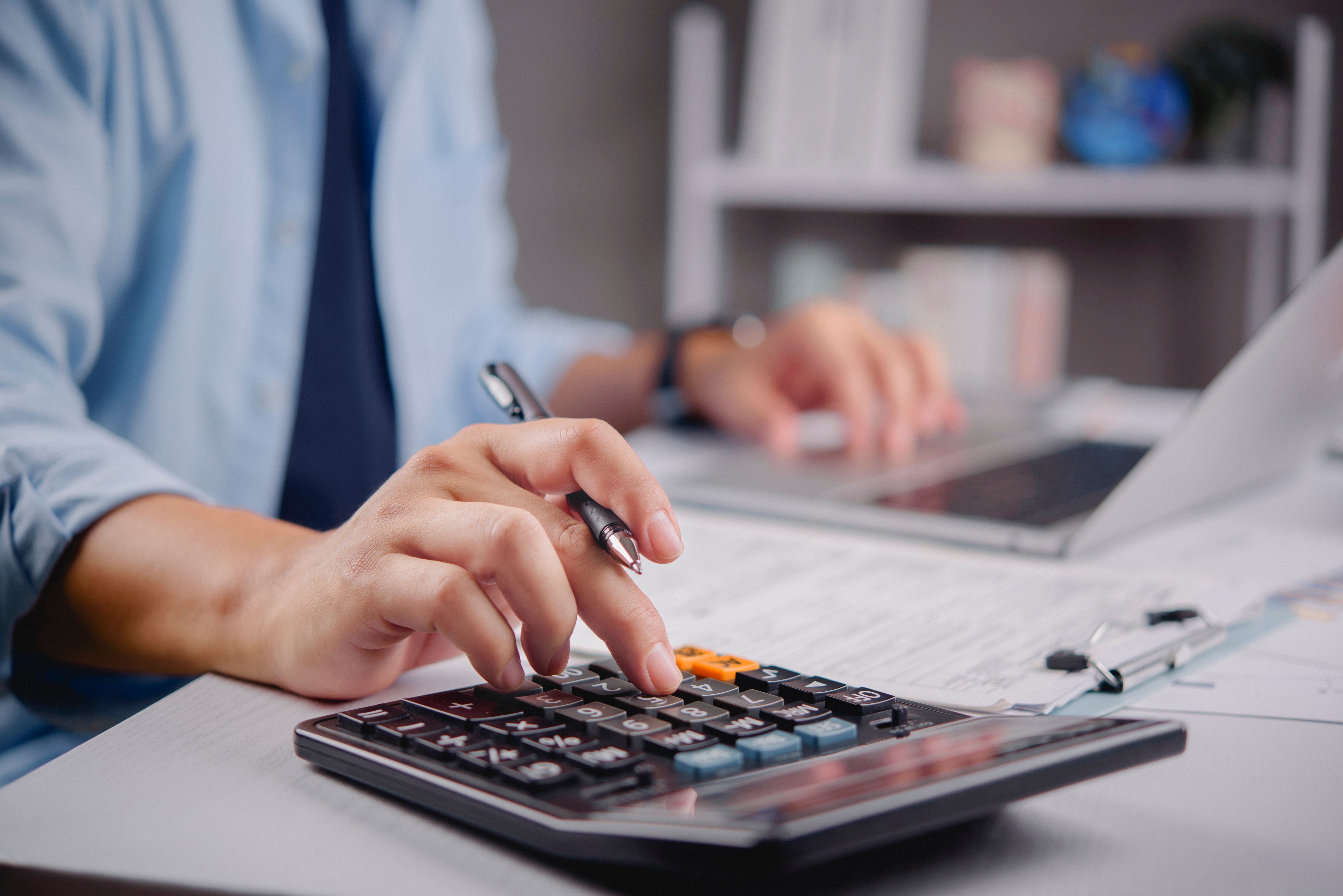 Man's hand typing on calculator